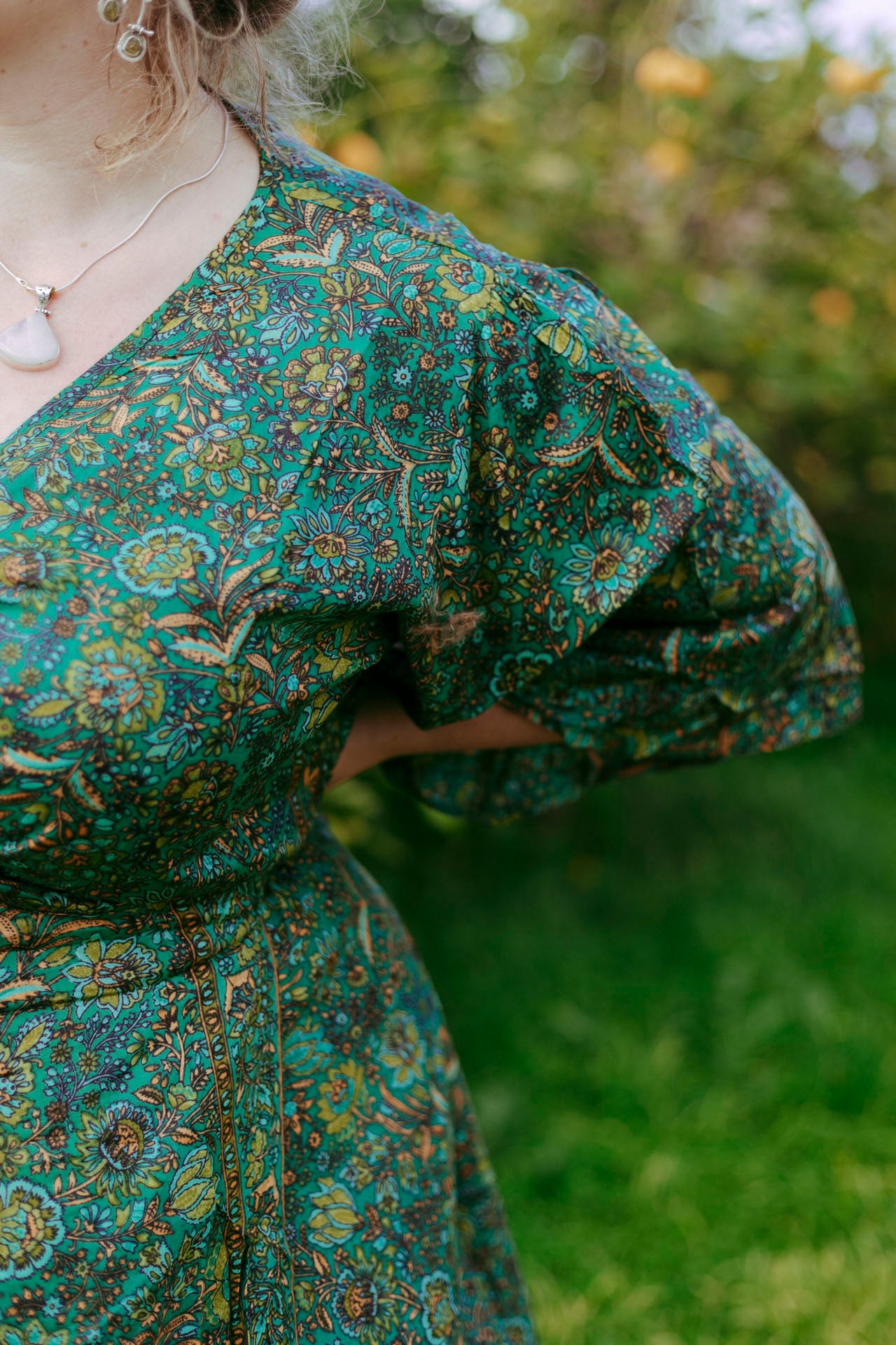 Person wearing a patterned dress with a blurred natural background