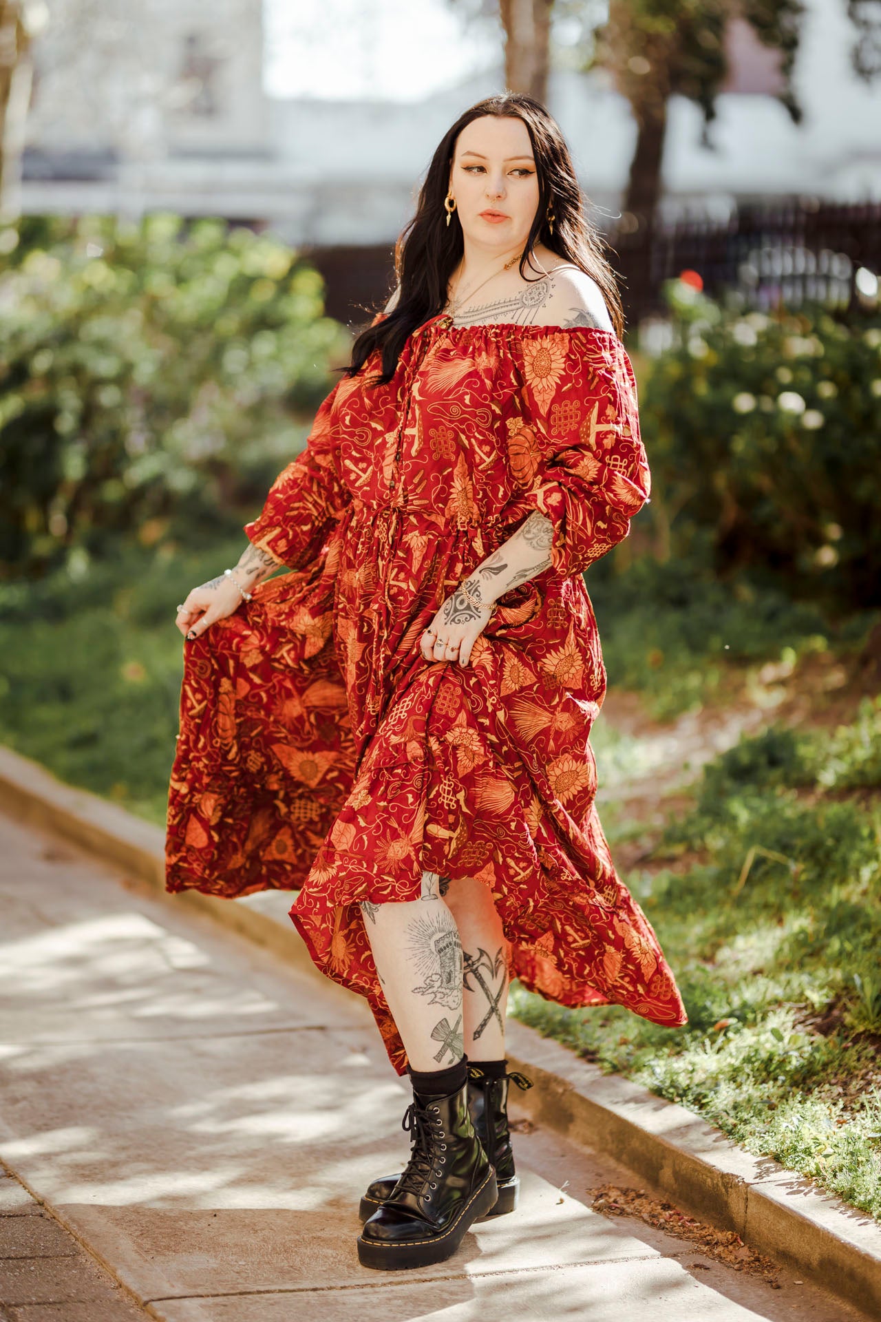 Woman in a red floral dress standing outdoors on a sunny day.