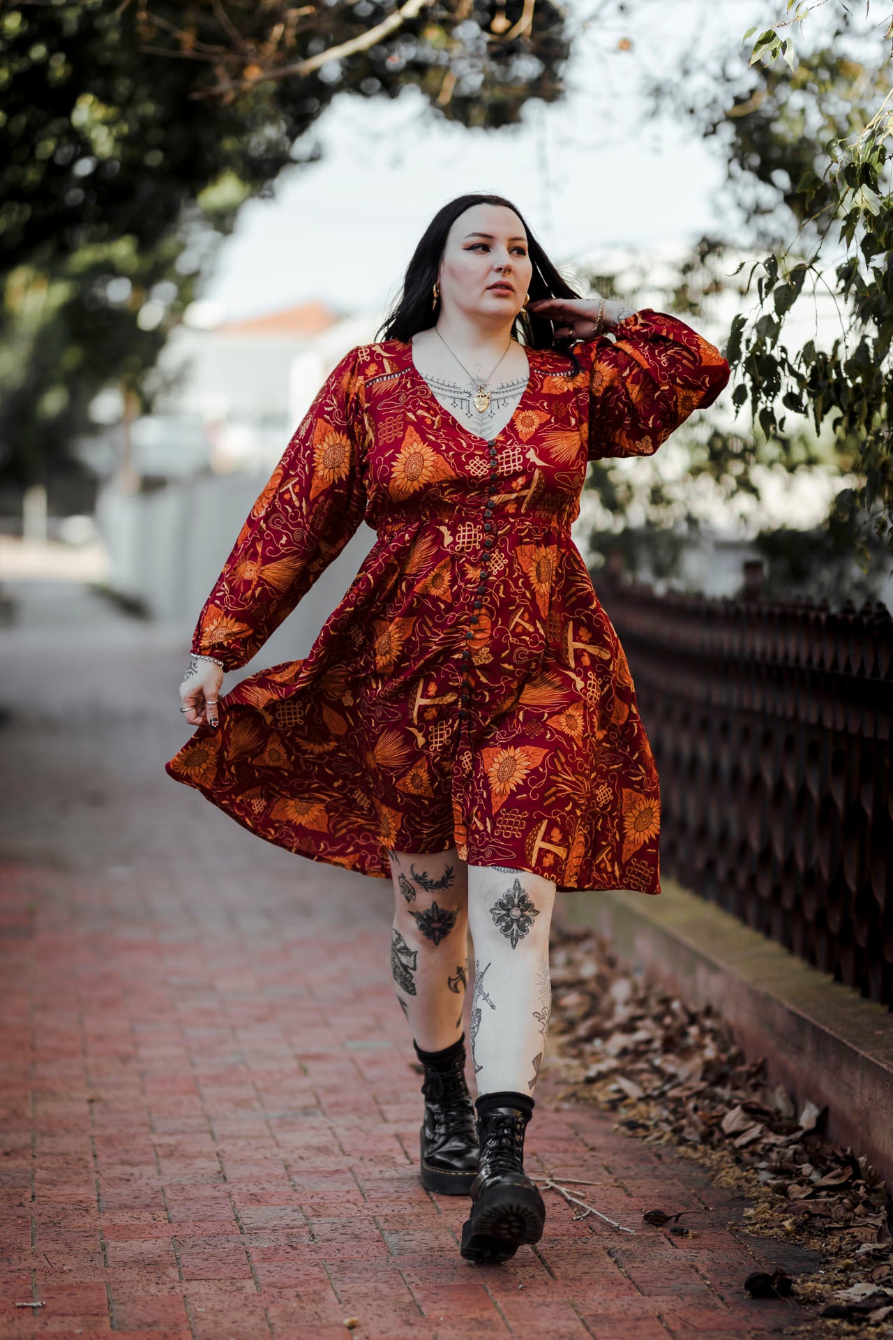 Woman in a patterned dress walking outdoors on a brick path.