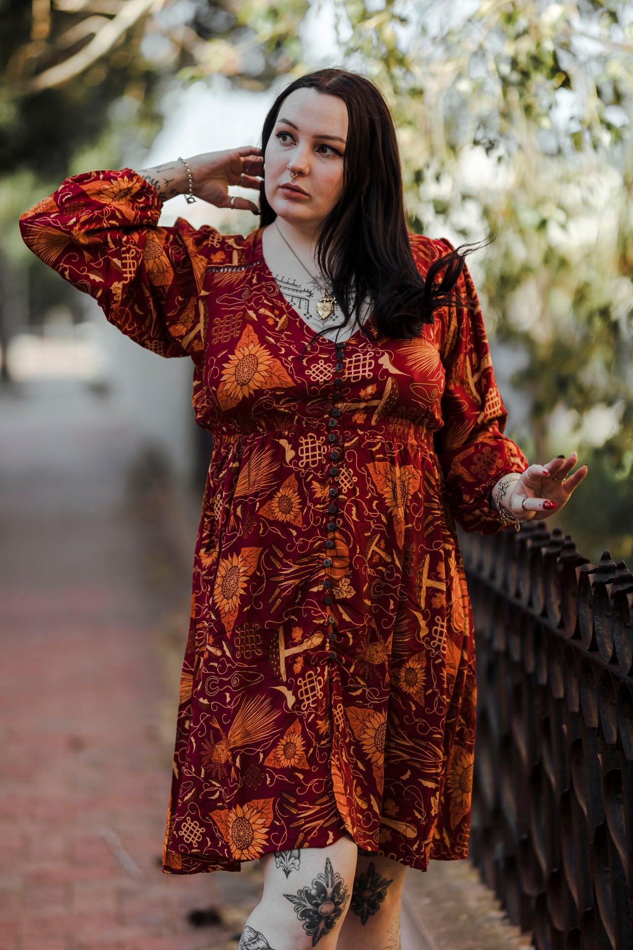 Woman wearing a patterned dress standing outdoors with blurred background