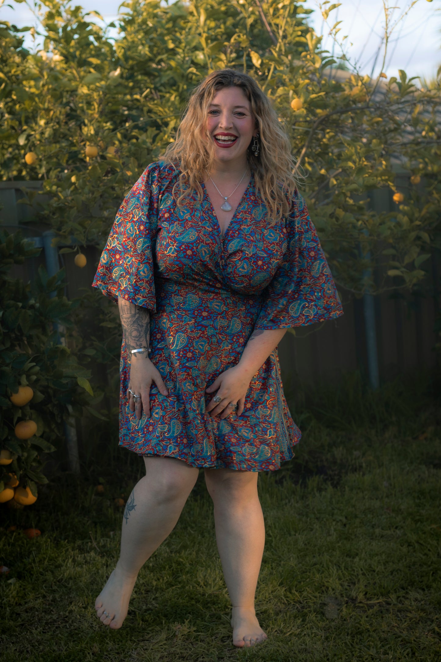 Woman in a floral dress standing outdoors with greenery in the background