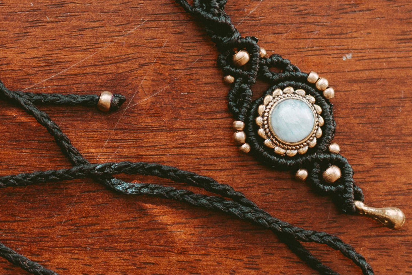 Macrame necklace with a central pendant on a wooden surface
