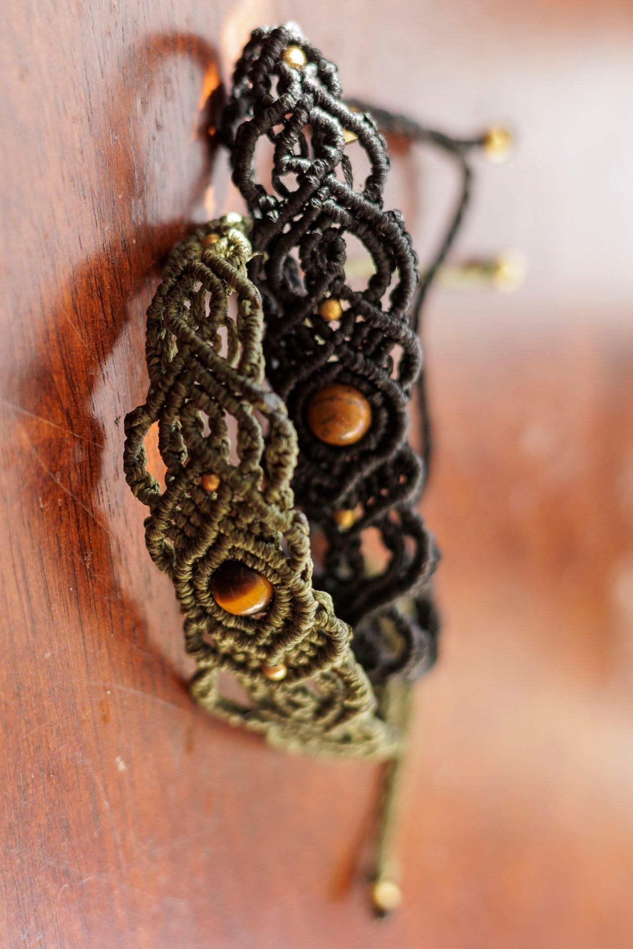 Two macrame headbands with wooden beads on a wooden surface