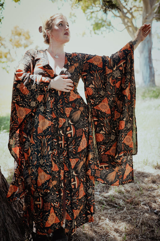 Woman wearing a patterned dress standing outdoors with trees in the background