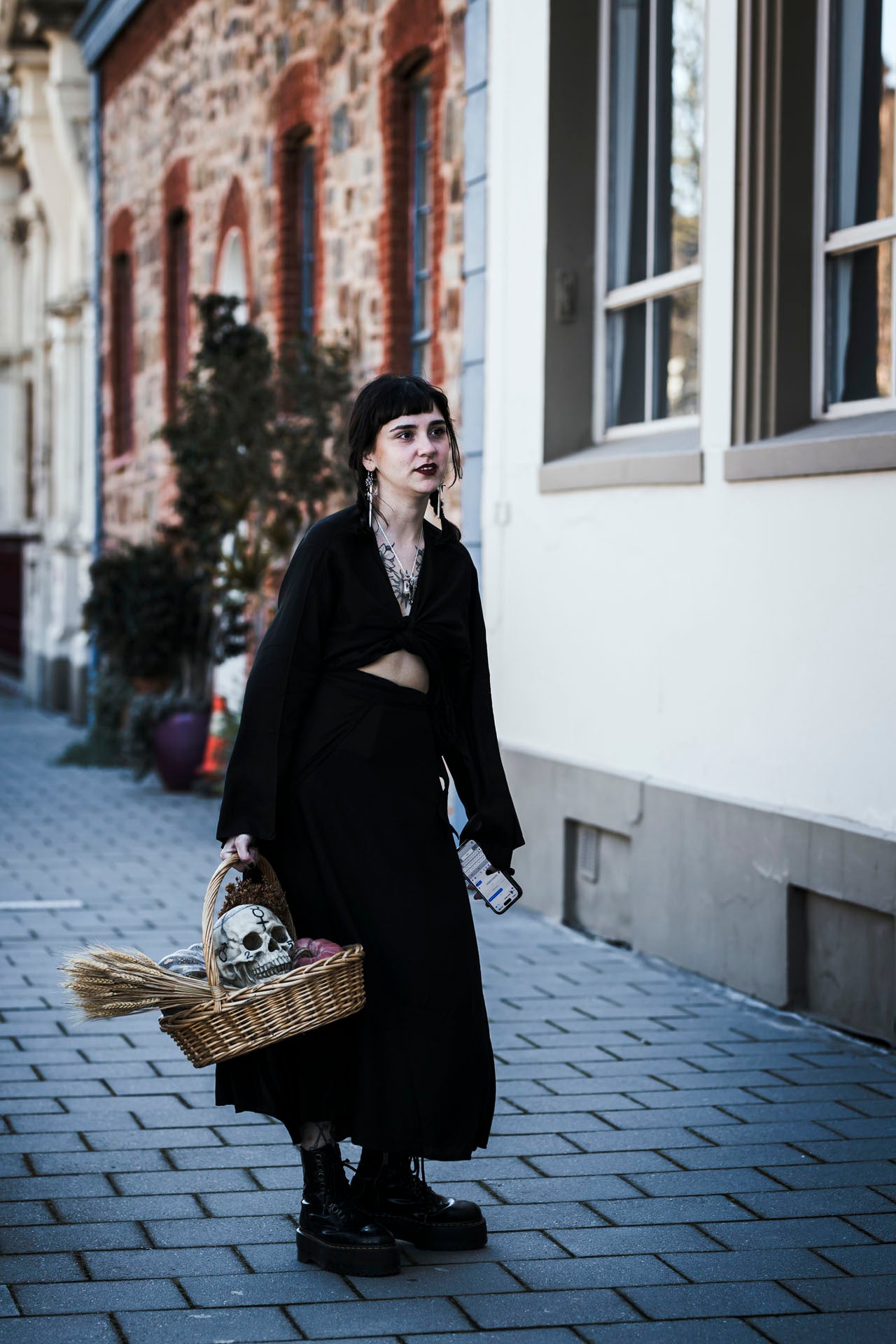 Person in black outfit with skull-themed basket on a street