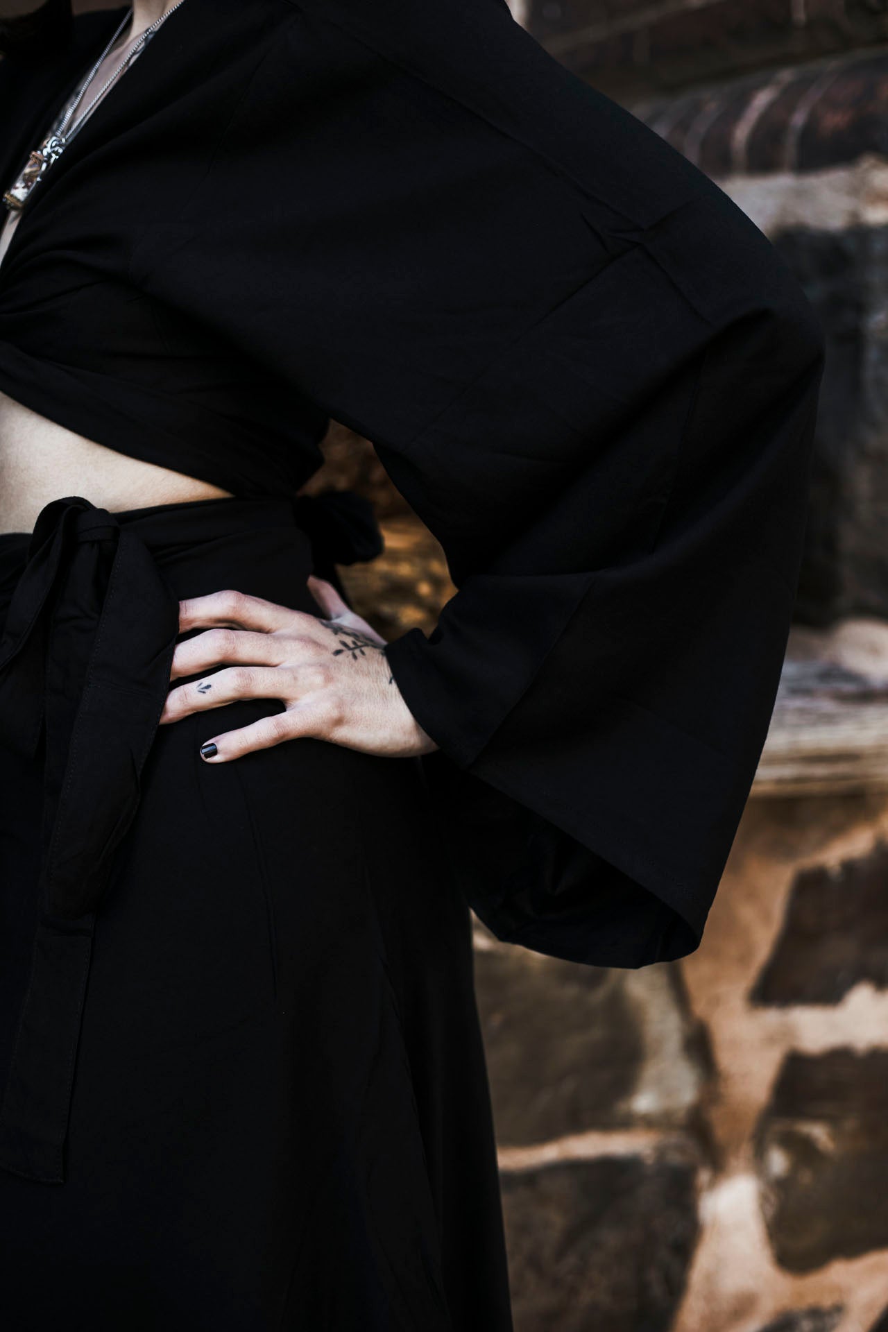 Person wearing a black outfit with a textured wall background