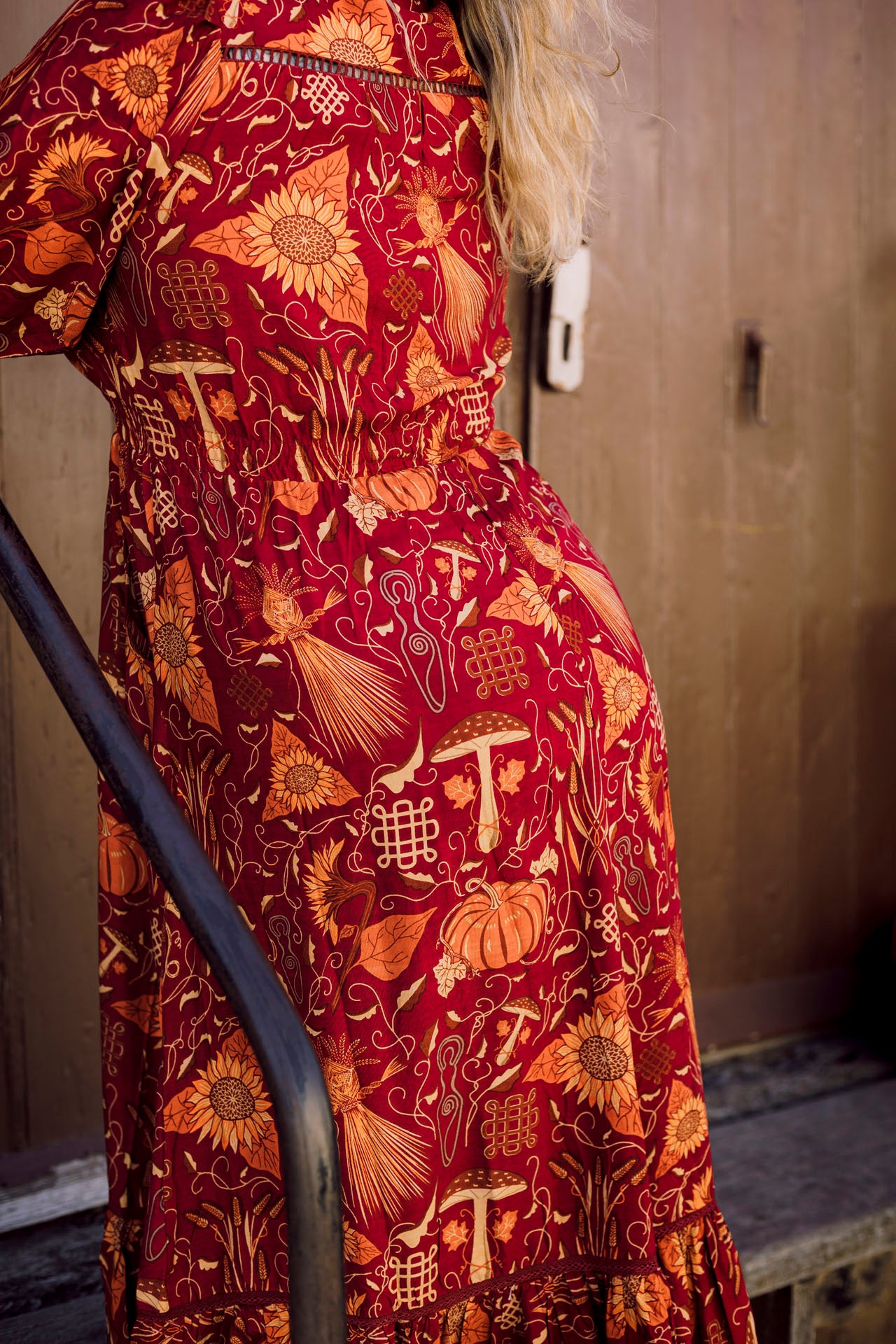 Red dress with intricate gold patterns worn by a person, against a neutral background.
