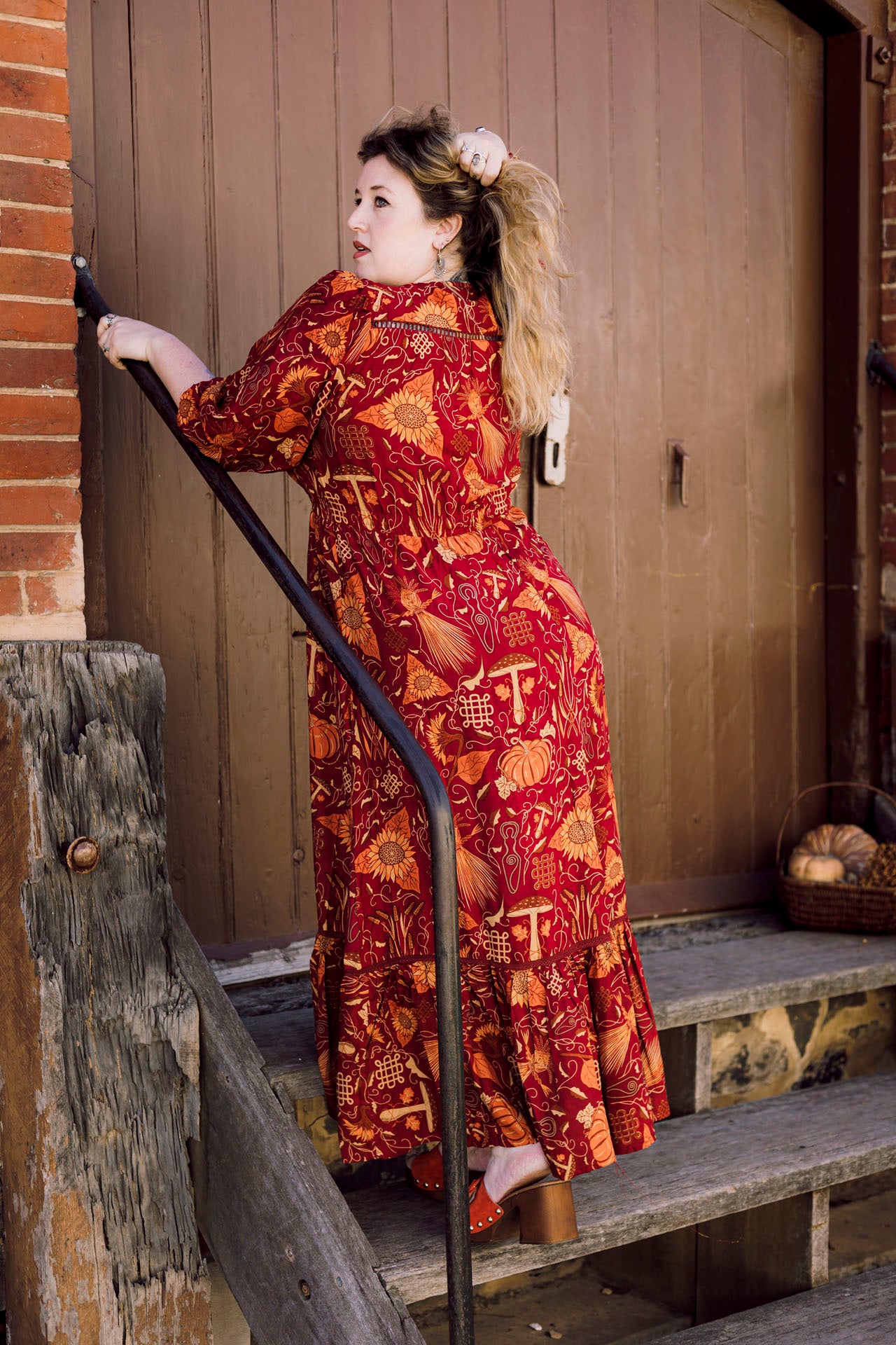 Woman in a red patterned dress standing on a set of stairs.