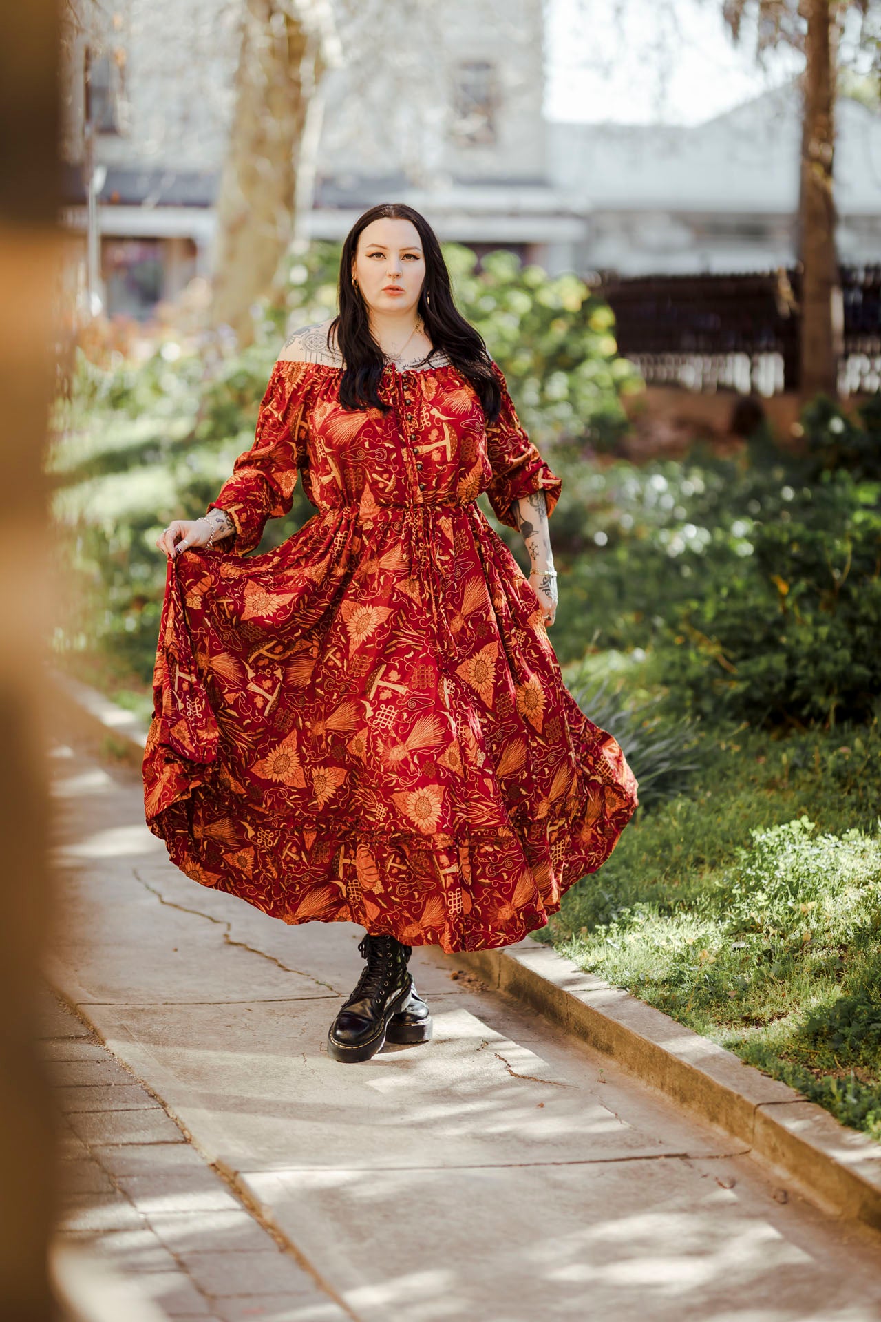 Woman in a red patterned dress walking on a path with greenery in the background