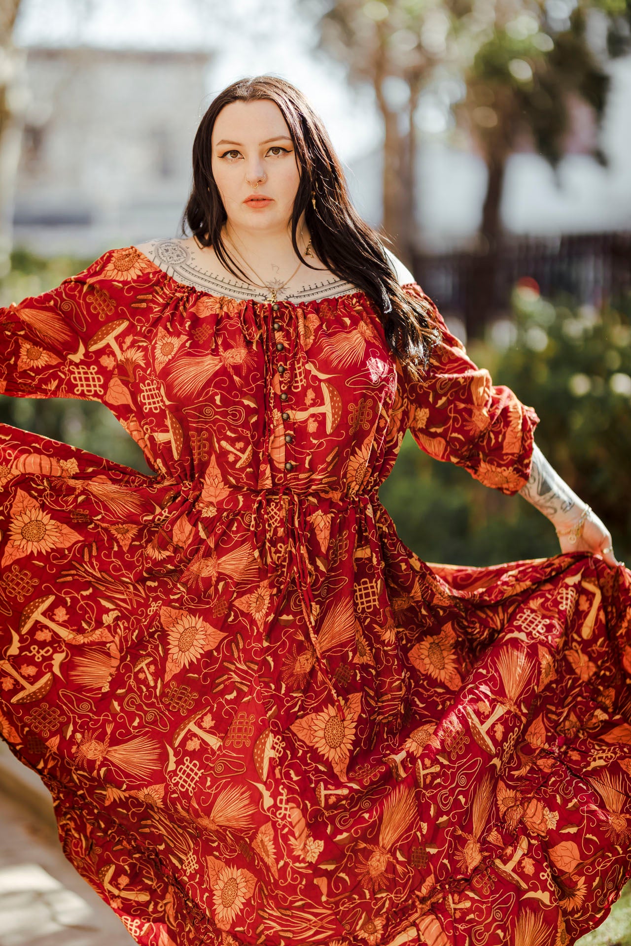 Woman wearing a red patterned dress with a blurred outdoor background