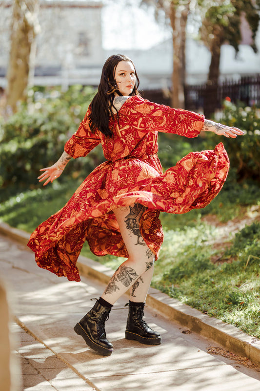 Person in a red floral dress dancing outdoors on a sunny day.