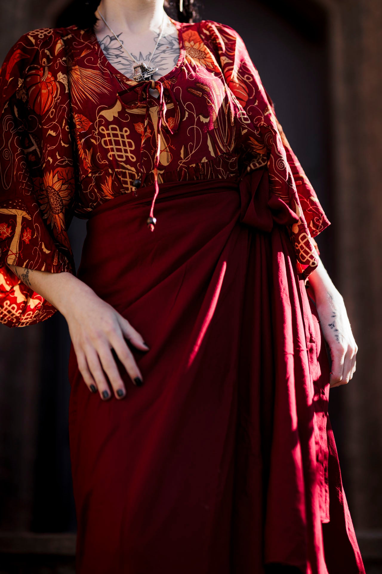 Mannequin wearing a red and gold patterned top with a draped red skirt against a dark background
