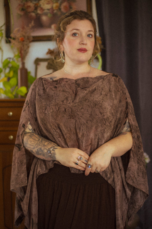 Woman wearing a brown textured top and black skirt with a dark background