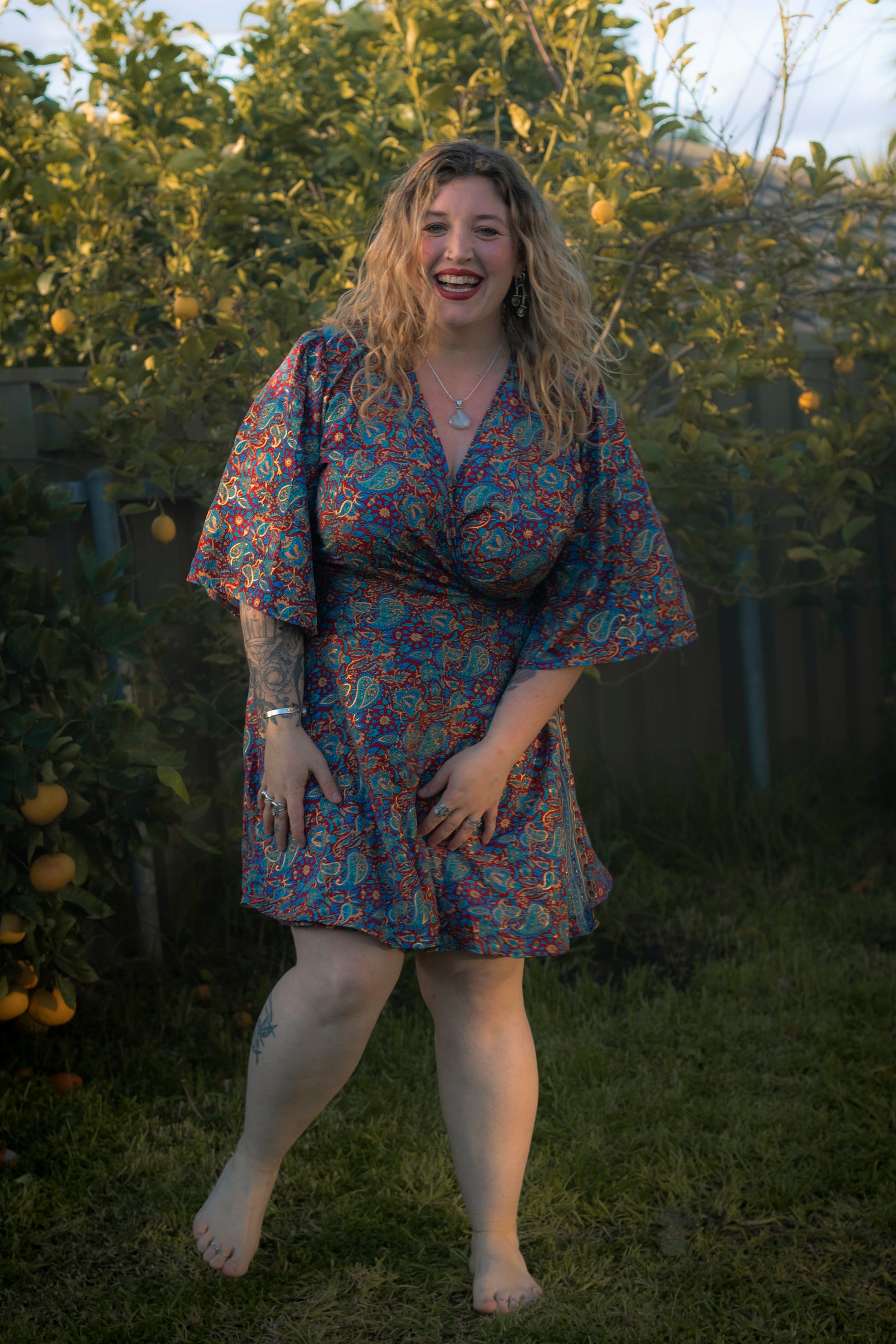 Woman in a floral dress standing outdoors with greenery in the background