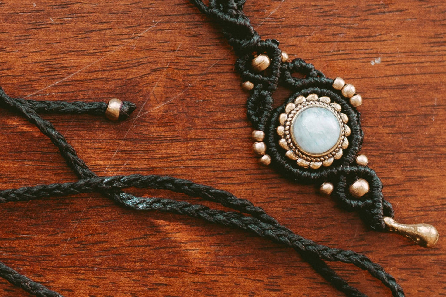 Macrame necklace with a central pendant on a wooden surface