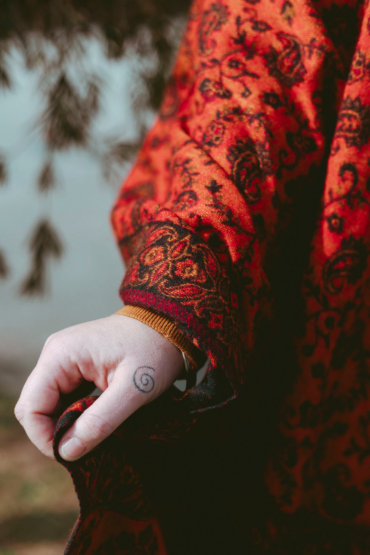 Person wearing a red patterned garment with a blurred natural background