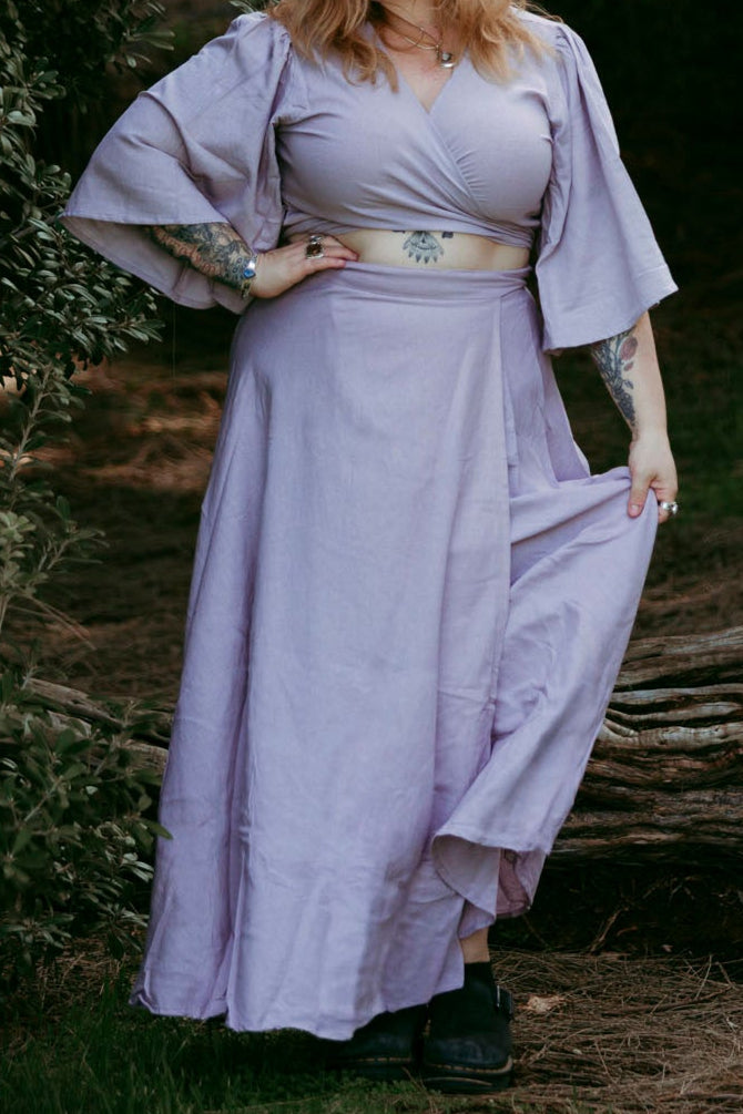 Woman in a purple dress standing in a forest setting