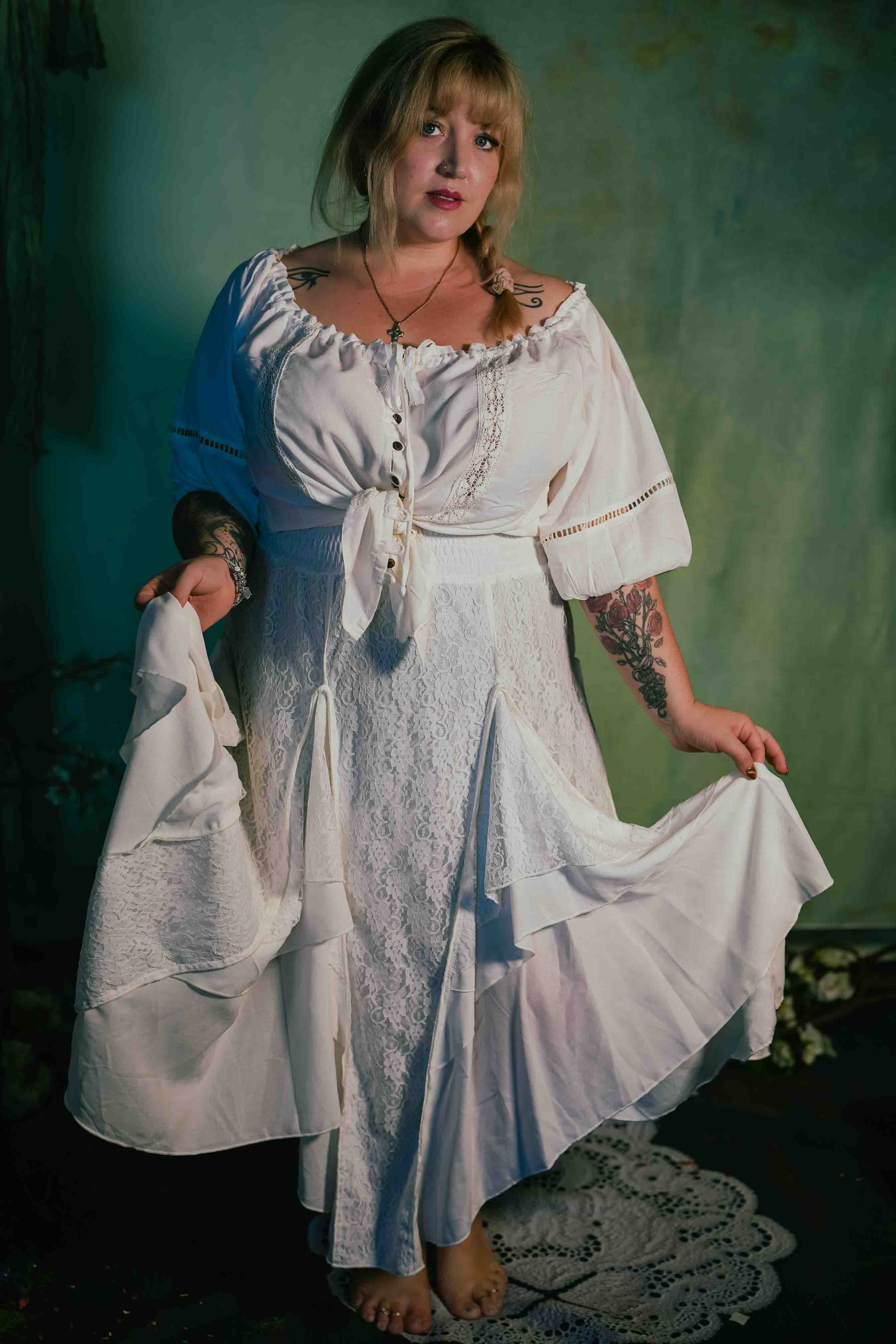 Woman wearing a white lace dress against a green wall.